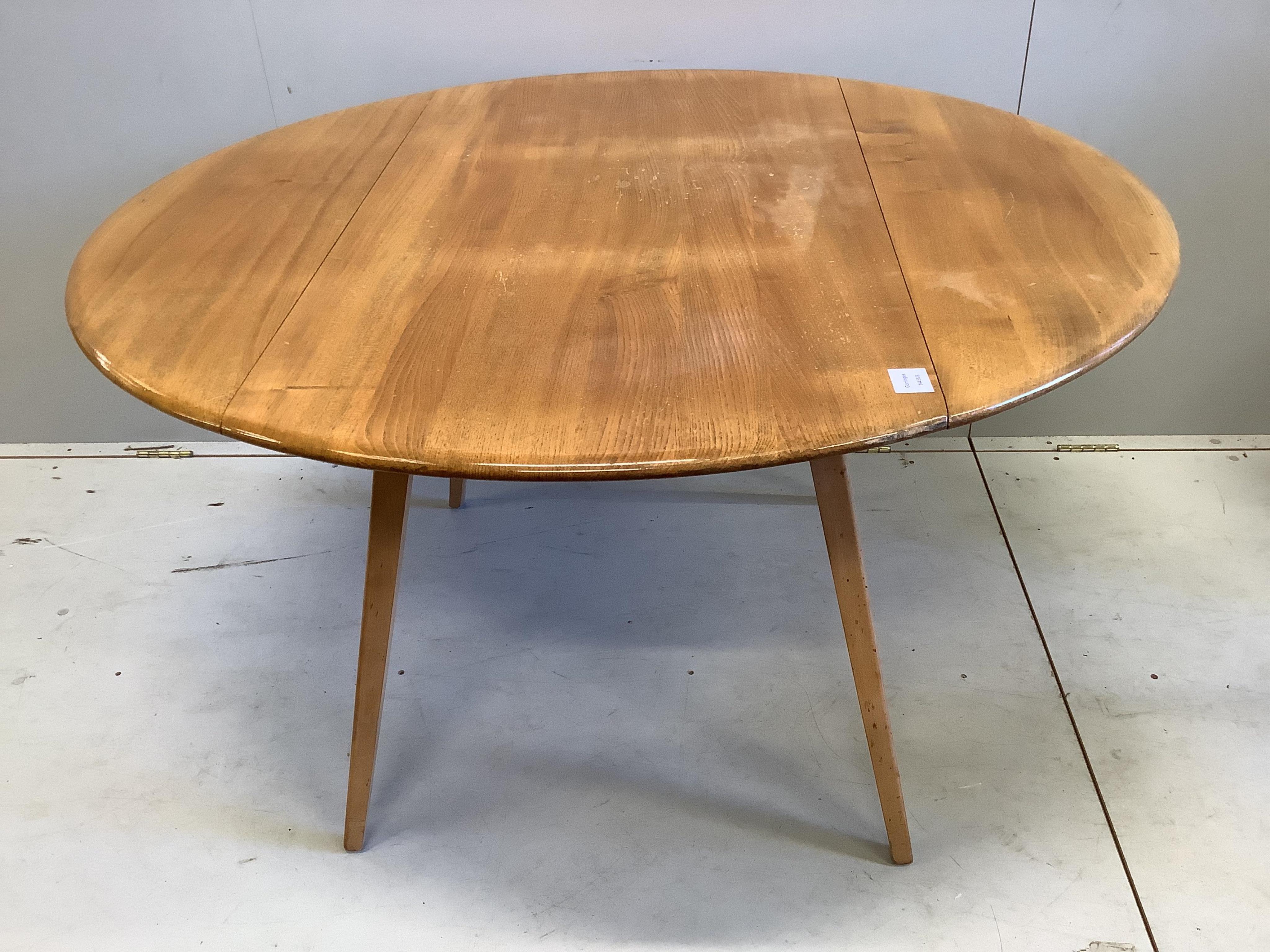 An Ercol circular elm and beech drop flap dining table, diameter 112cm, height 71cm, and four Ercol chairs. Condition - fair